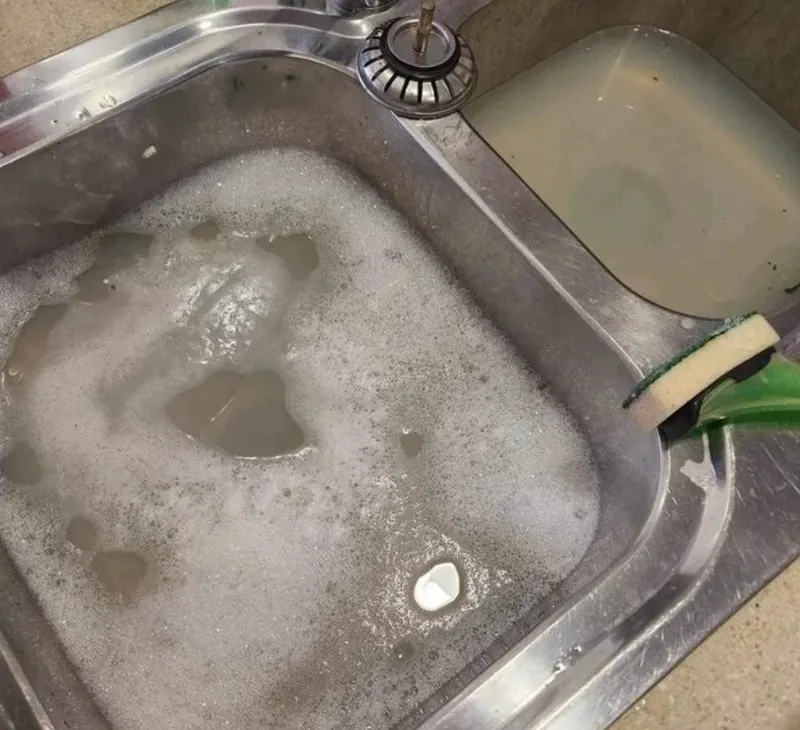 Verstopte rvs wasbak met schuimend stilstaand water